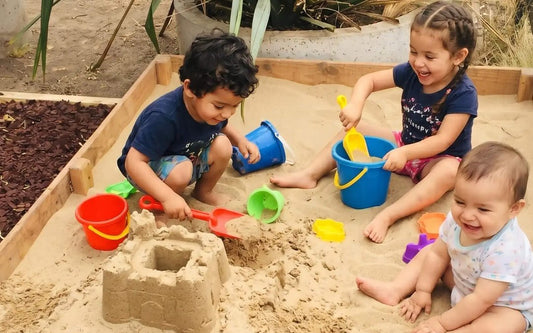 Niños jugando con arena clara y limpia Cimic en un arenero de madera