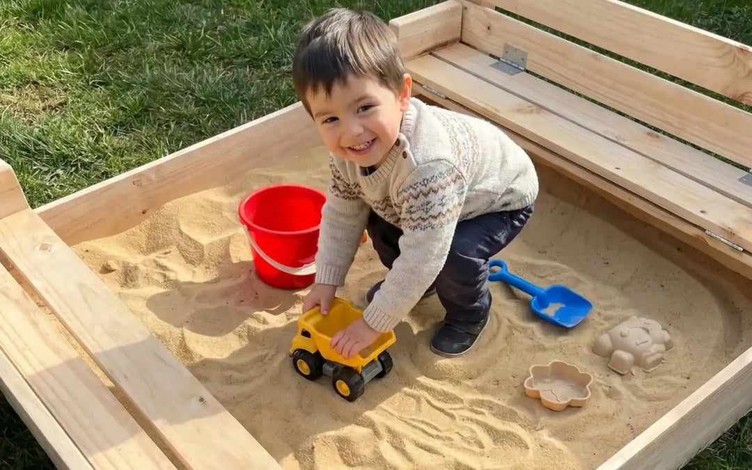 Niño feliz jugando en un arenero de madera con arena limpia Cimic