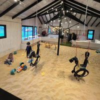 Espacio de juegos infantil con piso de arena y niños jugando