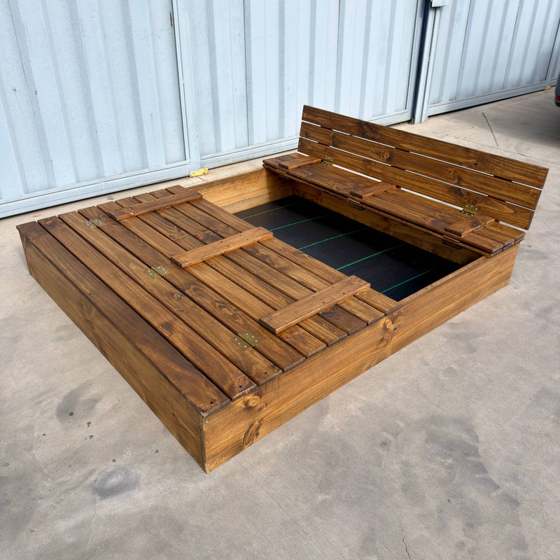 Arenero de madera para niños de 180 × 150 cm con una tapa cerrada y la otra abierta como banca con respaldo, malla antimaleza en el fondo