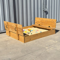 Arenero de madera para niños de 180 × 150 cm abierto, con las dos tapas convertidas en bancas