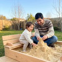Papá e hijo jugando con arena en el arenero de madera Cimic con banca plegable