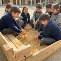 Niños de colegio jugando en un arenero de madera Cimic con arena limpia en el patio