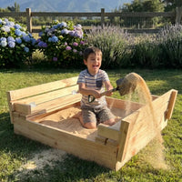 Niño jugando y lanzando arena limpia con la pala en el arenero de madera Cimic