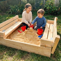 Niños jugando y haciendo castillos en el arenero de madera Cimic con bancas plegables
