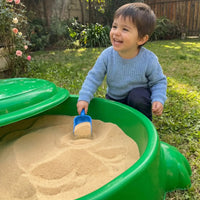 Niño jugando con arena limpia en el arenero plástico tortuga Cimic con la tapa abierta
