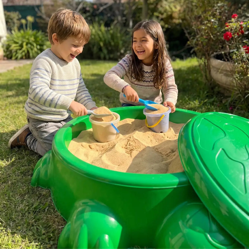 Dos niños jugando juntos con baldes y arena en el arenero plástico tortuga Cimic
