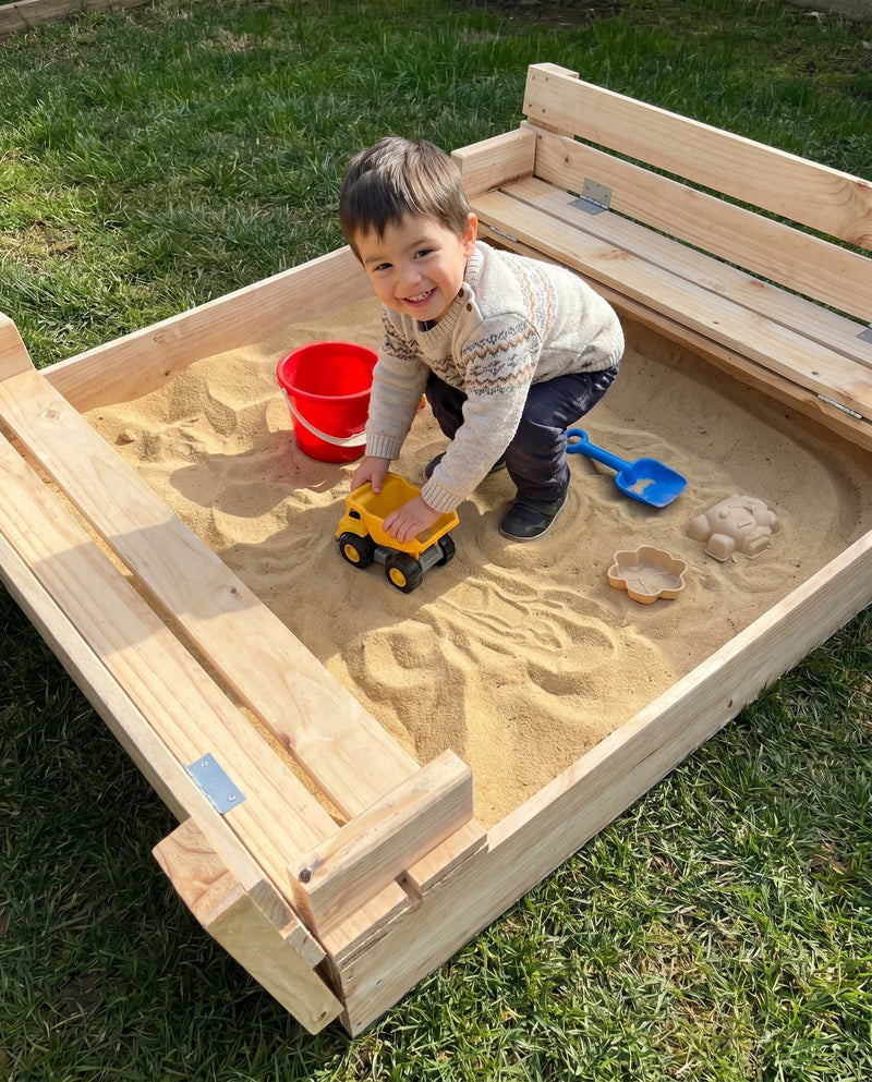 Niño feliz jugando con un camión de juguete en un arenero con arena para niños — Cimic