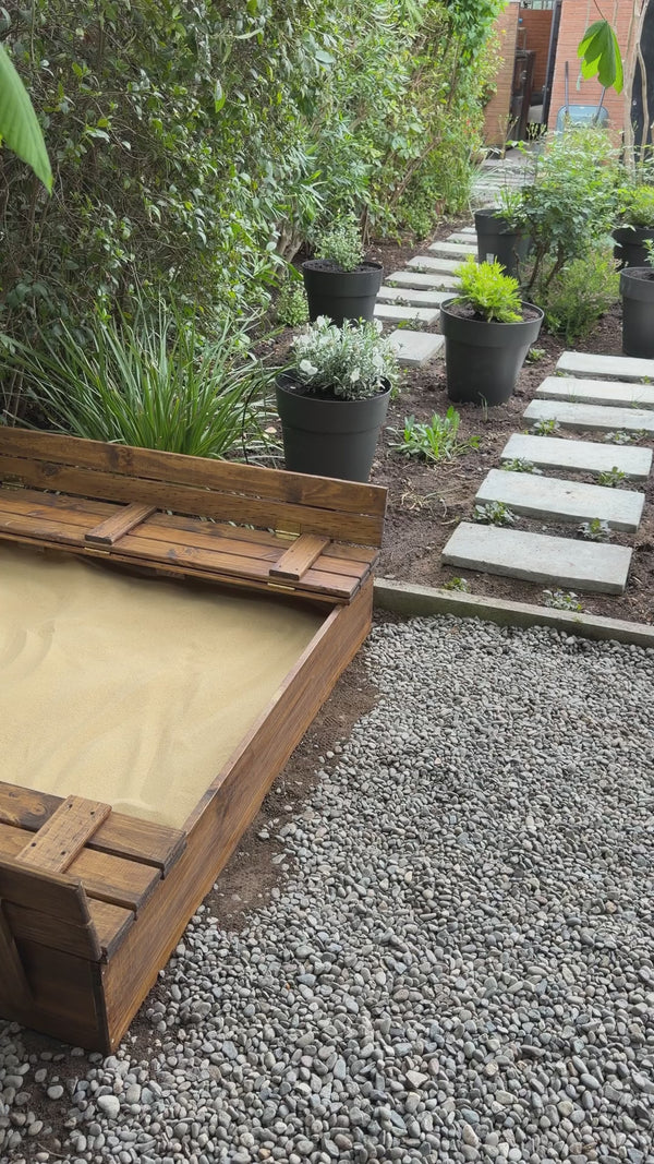 Arenero de madera para niños de 150 × 150 cm con arena instalado en el jardín — video